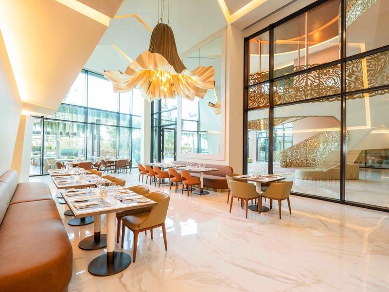 Světelná moderní restaurace s velkými okny, elegantním nábytkem a stylovým osvětlením.