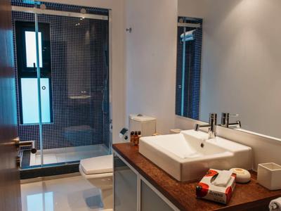 Modern hotel bathroom with wooden countertop, sink, toiletries, glass shower, and toilet.