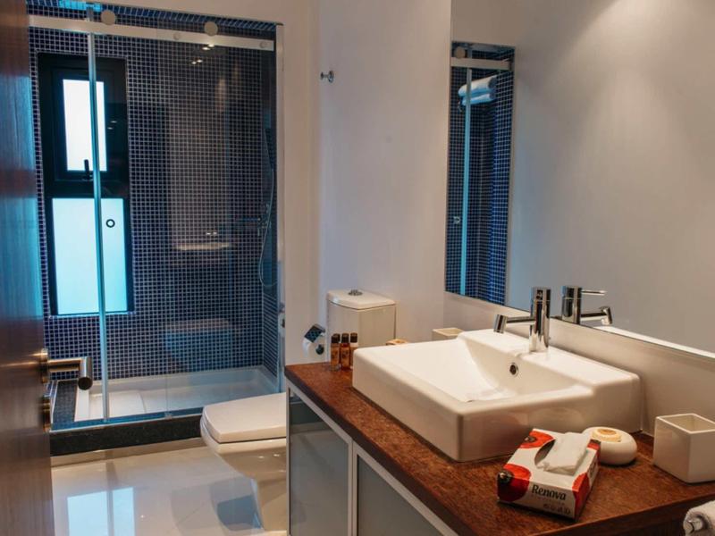 Modern hotel bathroom with wooden countertop, sink, toiletries, glass shower, and toilet.