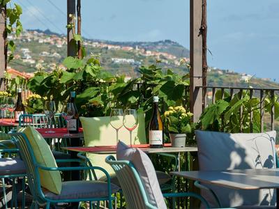 Sezení na balkóně s barevnými židlemi a rostlinami s výhledem na kopce a domy.