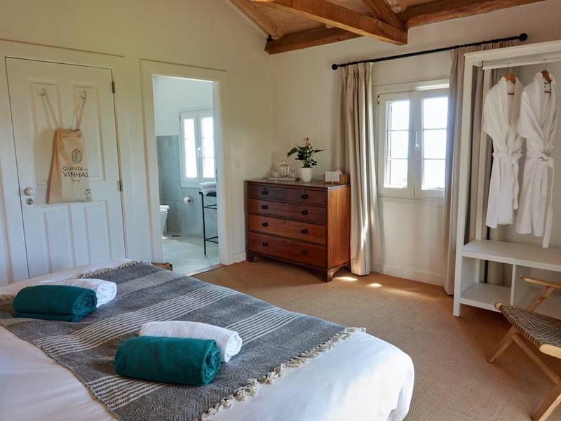 Jasně zařízená ložnice s pohodlnými postelemi, dřevěnou komodou a skříní.