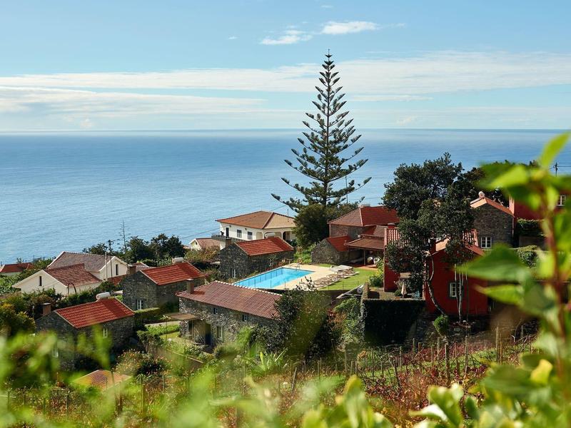 Pohled na vesnici s červenými střechami u pobřeží za slunečného počasí a modré oblohy.