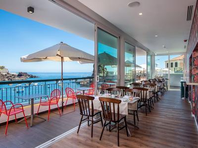 Restaurant met zeezicht en buitenzitplaatsen met parasol op een terras.
