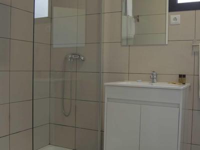 Moderne badkamer met douche, wit wastafelmeubel en grote spiegel.