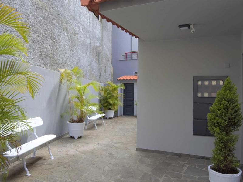 Binnenplaats met bankjes, planten in potten en grijze muren in een hotelomgeving.