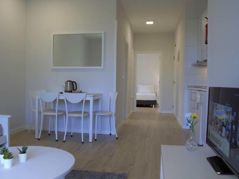 Moderne hotelkamerinterieur met gang, witte tafel, stoelen en tv.