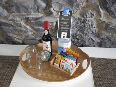 Vassoio con bicchiere da vino, bottiglia di vino e snack davanti a un muro di pietra