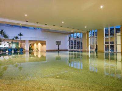 Piscina interna con grandi finestre, acqua trasparente e illuminazione moderna.