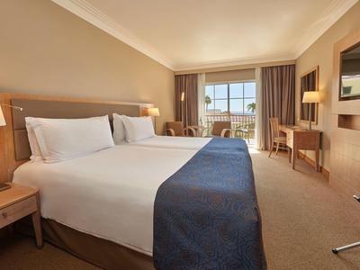 Camera d'hotel luminosa con letto grande e vista sul balcone.