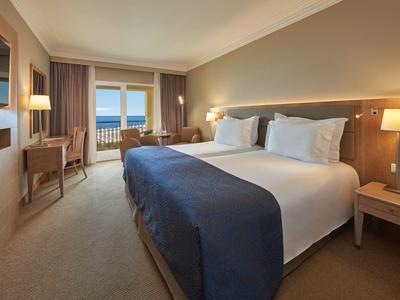 Modernes Hotelzimmer mit großem Bett, Balkon und Meerblick.