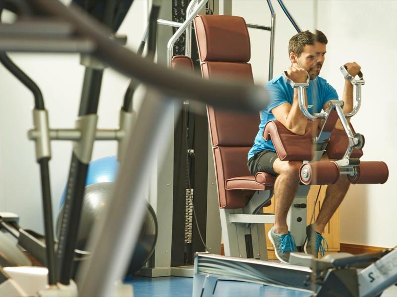 Uomo che si allena su una cyclette in una palestra luminosa