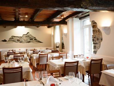 Accogliente sala da pranzo con soffitto a travi di legno e tavoli apparecchiati di bianco in un hotel.