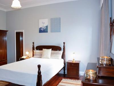 Camera luminosa con letto matrimoniale, comodino e mobili antichi in legno.