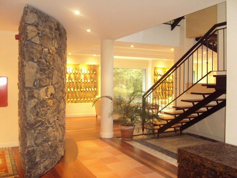 Ingresso dell'hotel luminoso con muro in pietra, scala e piante decorative.