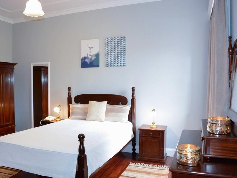 Camera luminosa con letto matrimoniale, comodino e mobili antichi in legno.