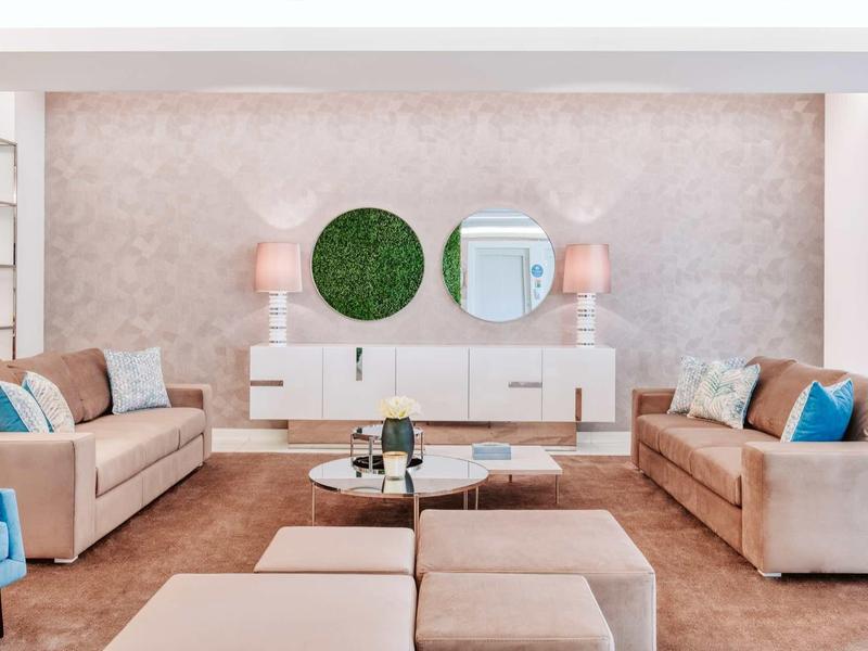 Modernes Wohnzimmer mit zwei beigen Sofas, Teppich, runden Spiegeln und weißem Sideboard.