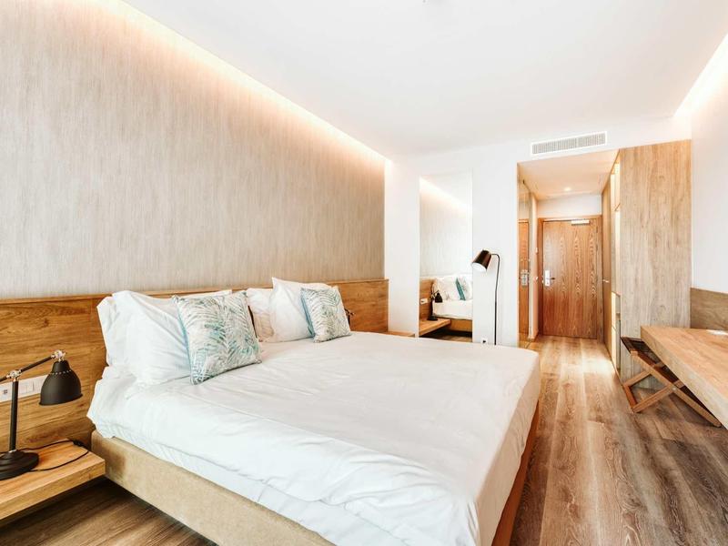 Modern eingerichtetes Schlafzimmer mit Doppelbett, Holzmöbeln und warmem indirektem Licht.