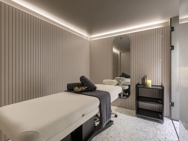 Sala trattamenti moderna con lettino da massaggio e illuminazione rilassante.