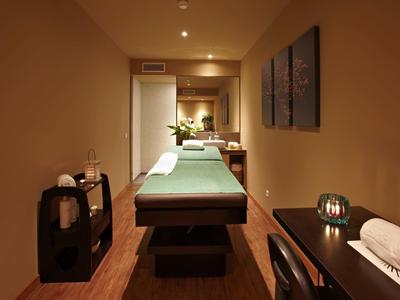 Accogliente stanza ben illuminata per il benessere con lettino da massaggio e elementi decorativi.