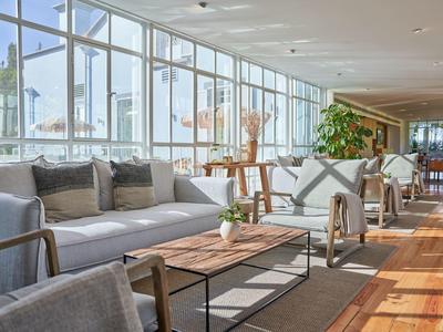 Zona lounge luminosa con divani e grandi finestre con vista sul porto.