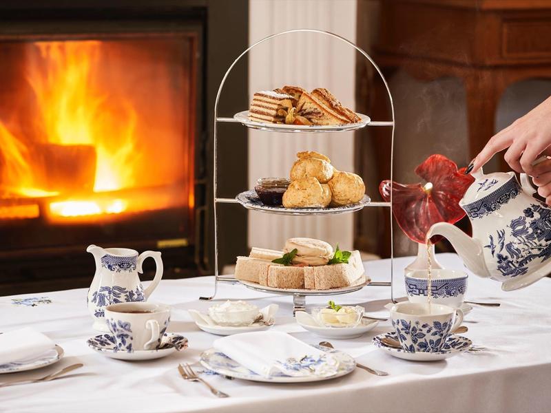 Tavola elegante con tè, dolci e camino per pomeriggi accoglienti in hotel.
