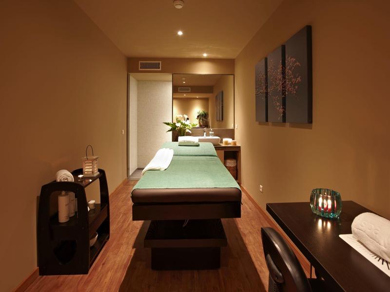 Accogliente stanza ben illuminata per il benessere con lettino da massaggio e elementi decorativi.