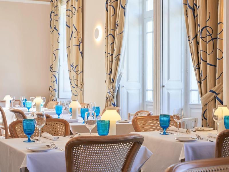 Ristorante elegante con bicchieri blu e tovaglie bianche in una stanza luminosa.