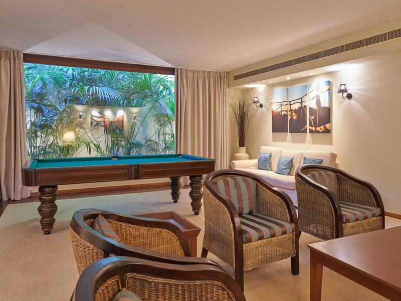 Un elegante salotto con tavolo da biliardo, sedie in rattan e una finestra con vista sul verde.