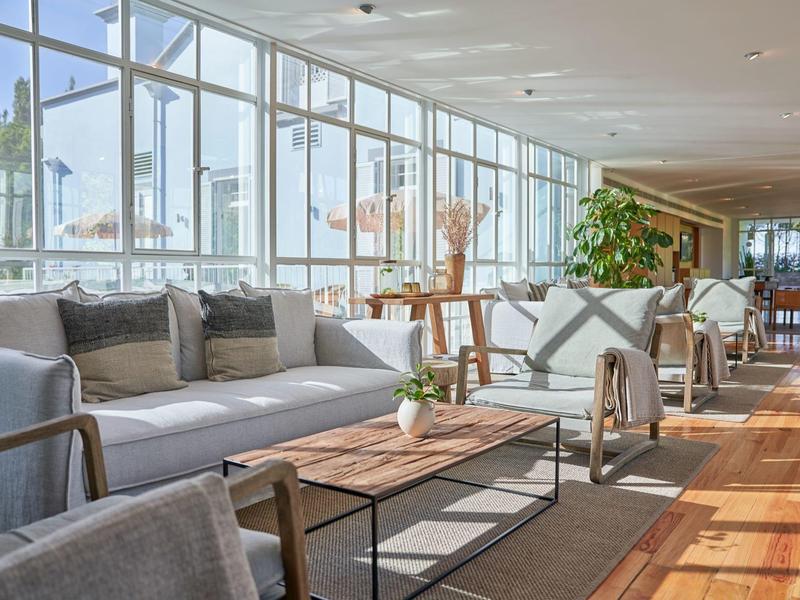 Zona lounge luminosa con divani e grandi finestre con vista sul porto.