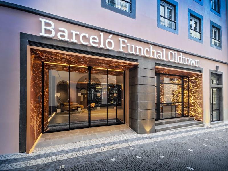 Verlichte gevel van Barcelo Funchal Oldtown hotel met grote ramen en marmeren accenten.