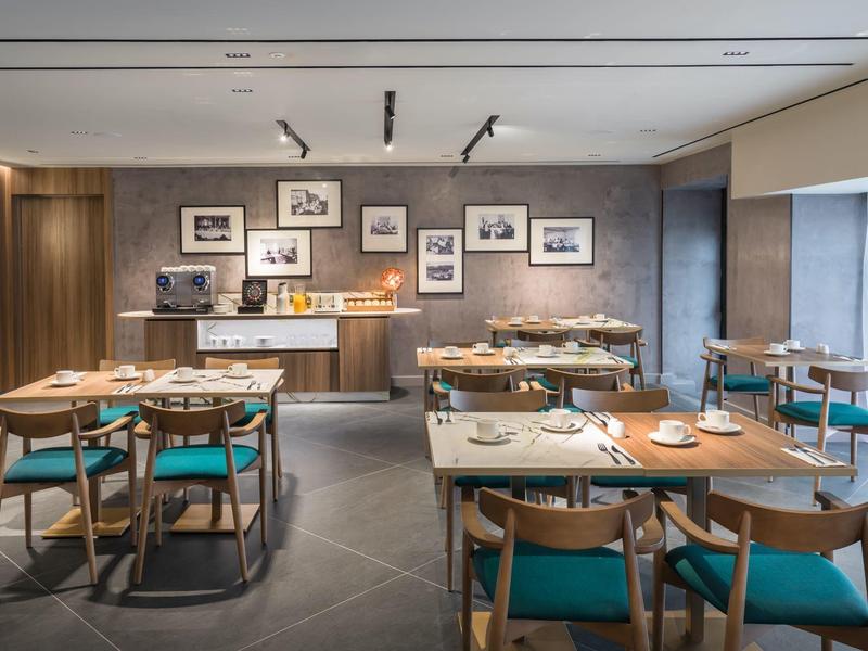 Modern restaurant met houten tafels en turquoise stoelen in een elegante hotelsfeer.