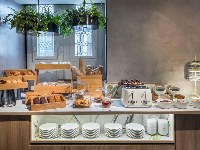 Buffet met broodroosters, broodjes en wit servies in een moderne hotellobby