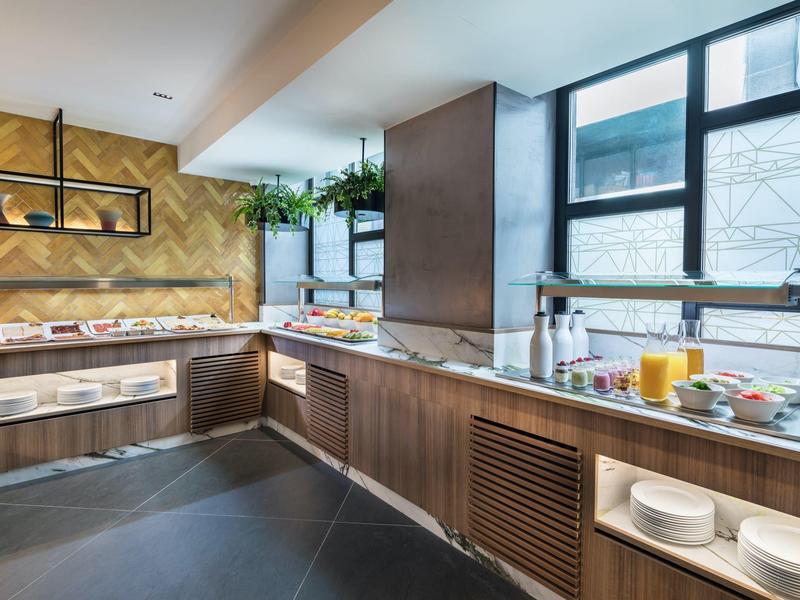 Lichte ontbijtruimte met buffet en grote ramen, moderne inrichting met houten meubels.