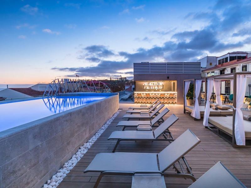 Modern hotelzwembad met ligbedden en sfeerverlichting bij zonsondergang