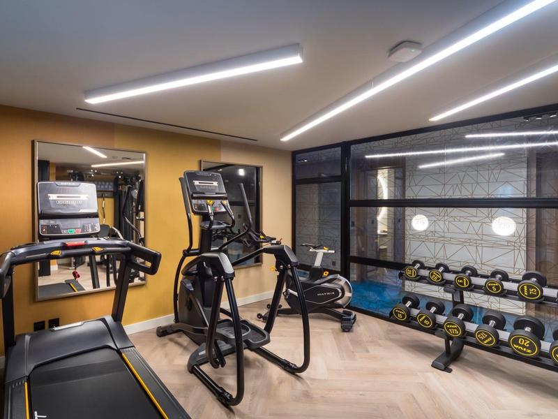 Moderne fitnessruimte met loopband, hometrainer, spiegel en halters in een hotel.