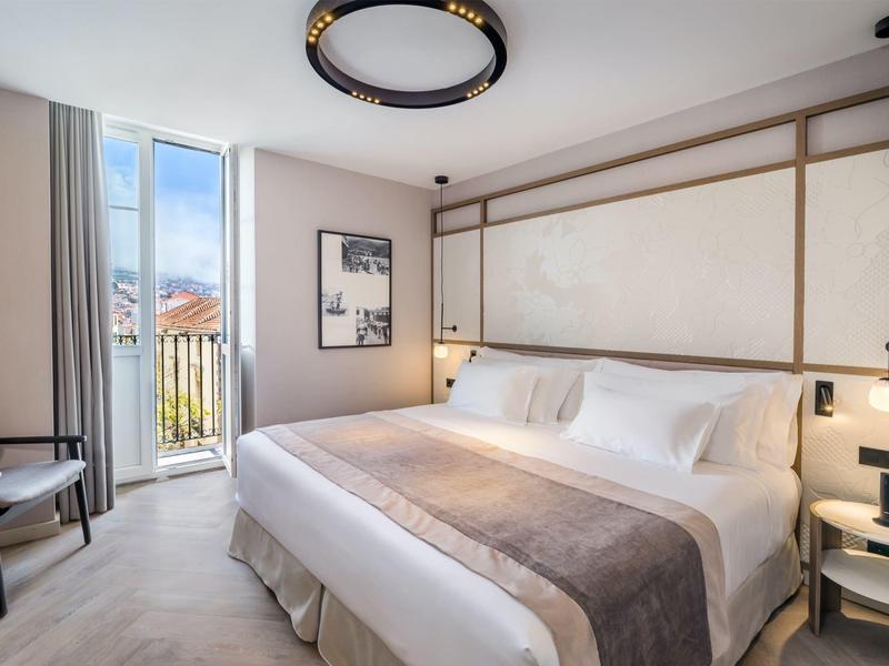 Moderne hotelkamer met groot bed, balkon en elegante verlichting.