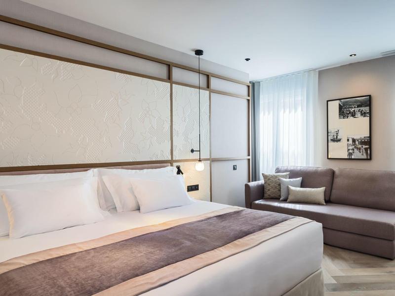 Modern hotelkamer met groot bed en knusse zithoek bij het raam.