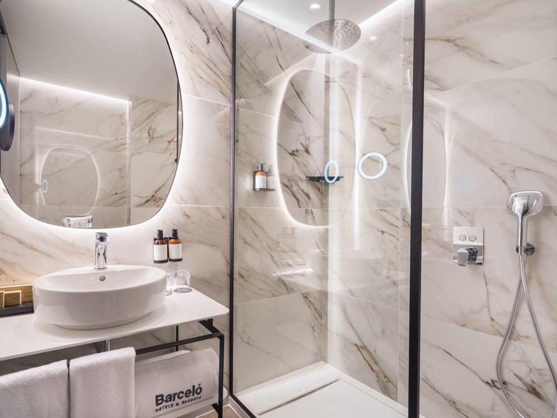 Moderne badkamer met verlichte spiegel, wastafel en douche met glazen wand.