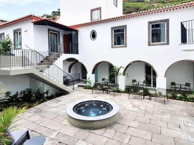 Cour intérieure d'hôtel avec une fontaine ronde et des bâtiments blancs avec des arches.