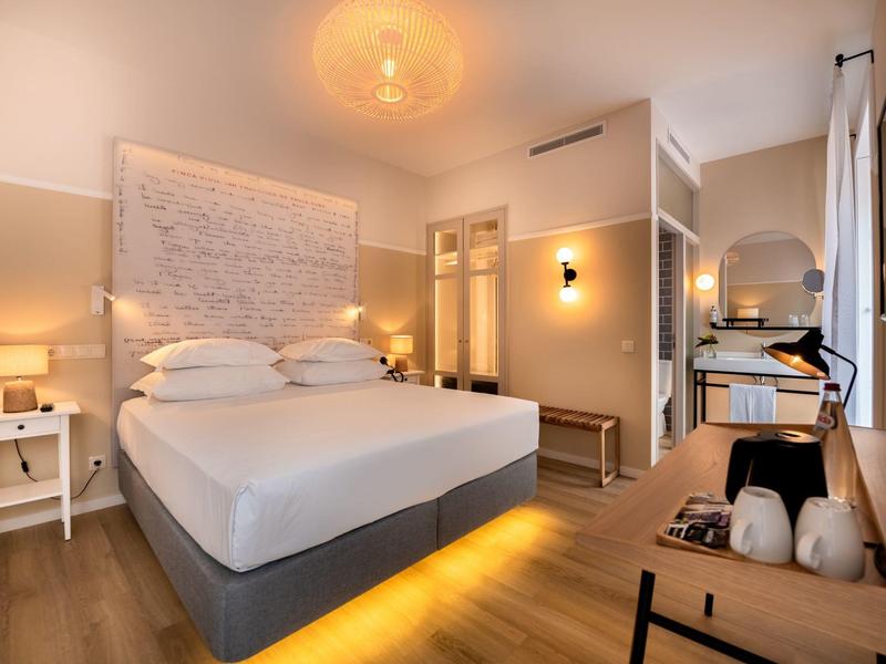 Chambre d'hôtel moderne avec grand lit, éclairage chaleureux et décoration intérieure élégante.