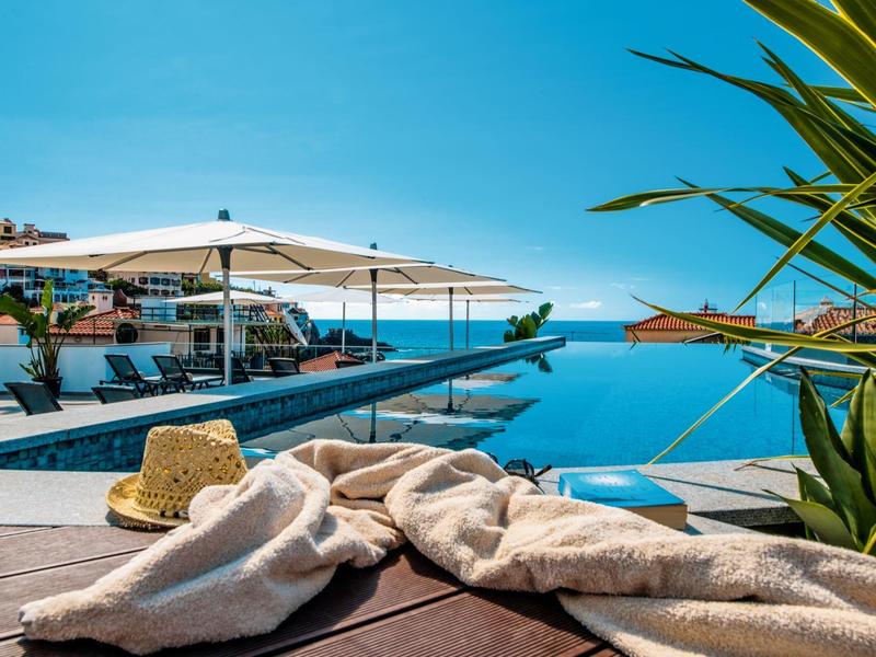 Espace piscine avec chaises longues surplombant la mer et le ciel bleu