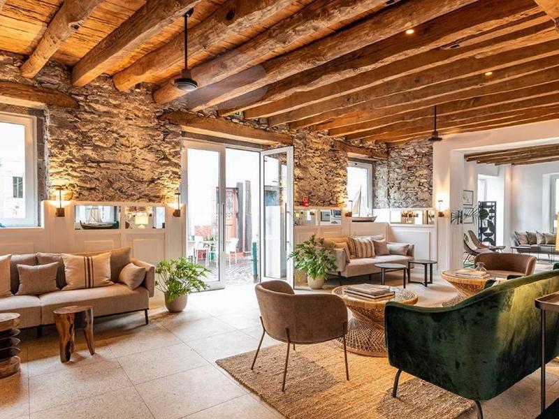 Coin salon d'hôtel confortable avec poutres en bois apparentes, mur en pierre et sièges confortables.