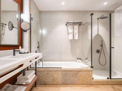 Modernes Badezimmer mit Badewanne, Dusche und Doppelwaschbecken in warmen Naturtönen.