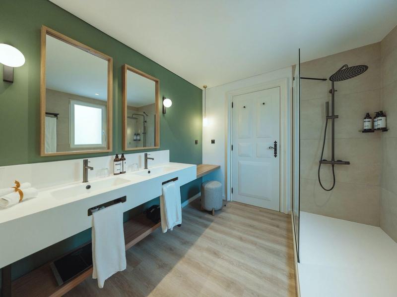 Modern bathroom with double sinks, mirrors, and walk-in rain shower.