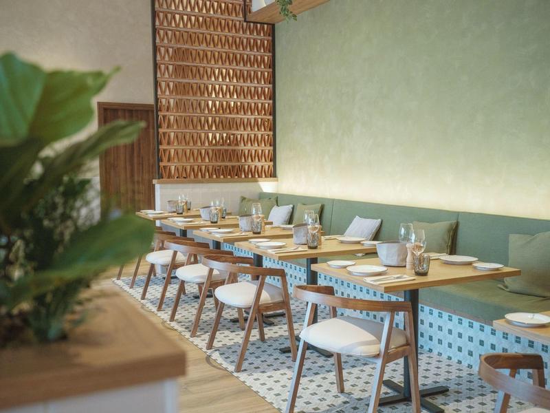Brightly lit breakfast room with tables, chairs, and plate settings.