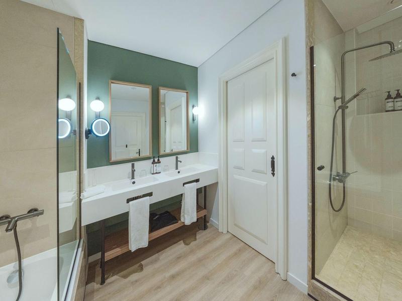 Modern bathroom with double sinks, mirrors, shower, and bathtub.