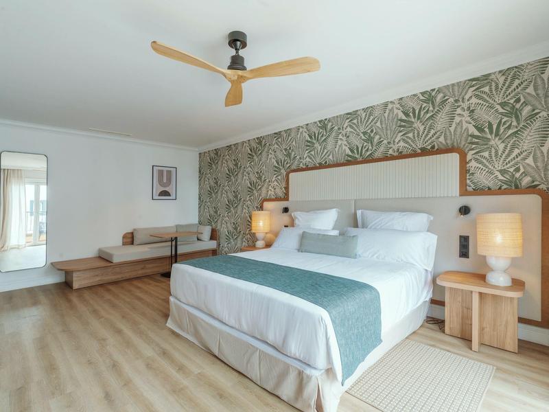 Bright bedroom with large bed, patterned wall, and modern wooden flooring.