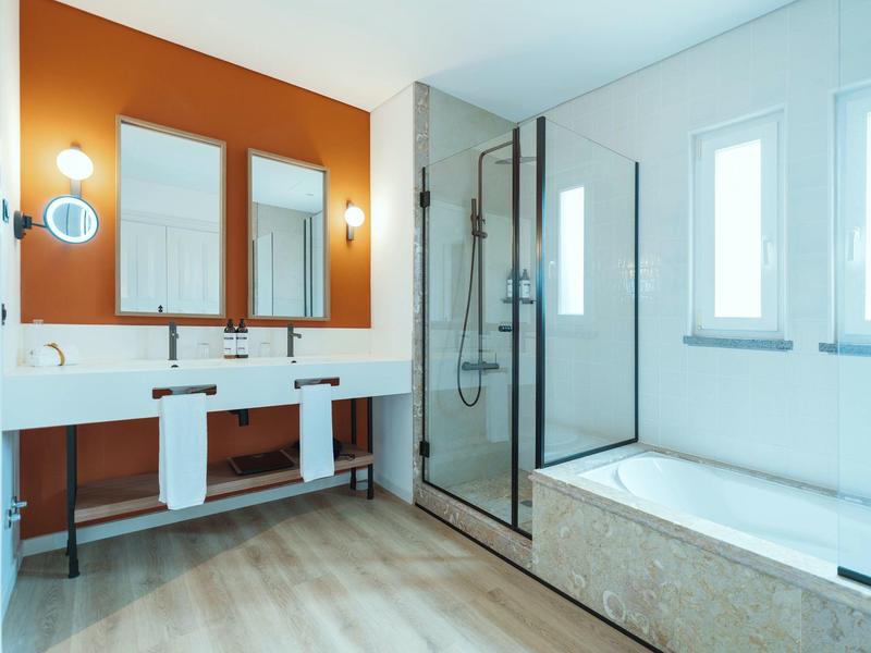 Modern bathroom with two sinks, bathtub, and walk-in shower.