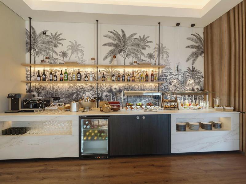 Modern hotel bar area with elegant lighting and tropical wall decoration.