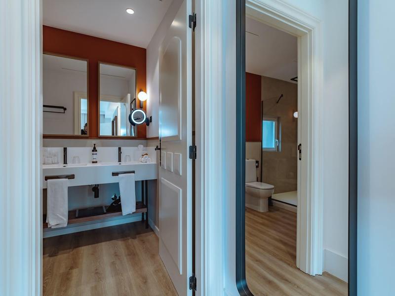 View into two adjacent bathrooms with modern fixtures and clean design.